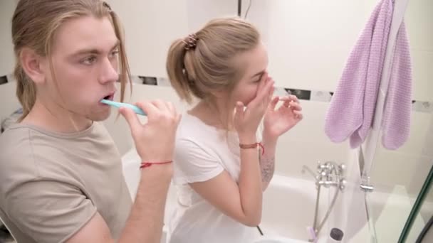 Young couple in bathtub. Man brushes teeth, girl rubs face, smiles. Close-up — 비디오