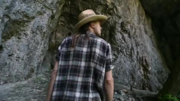 Man goes to cave, looking around. Closeup, camera follows. The view from back. — Stock Video