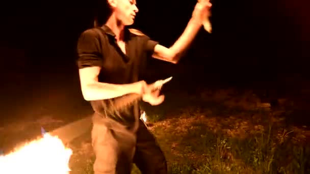 Primo piano. Giovane uomo al buio raffigura torcia rotante ardente. Mostra antincendio — Video Stock