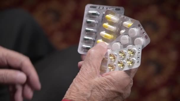 Primer plano de una tableta en las manos de una anciana. El concepto de elegir medicamentos en la vejez — Vídeo de stock