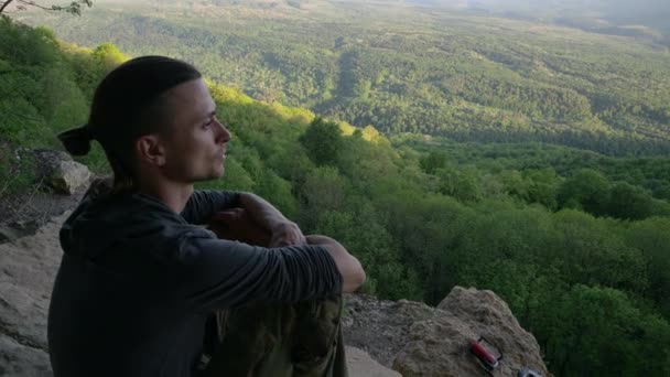 Perfil de primer plano del hombre, mira cuidadosamente desde la cima en el valle. Verano soleado — Vídeo de stock