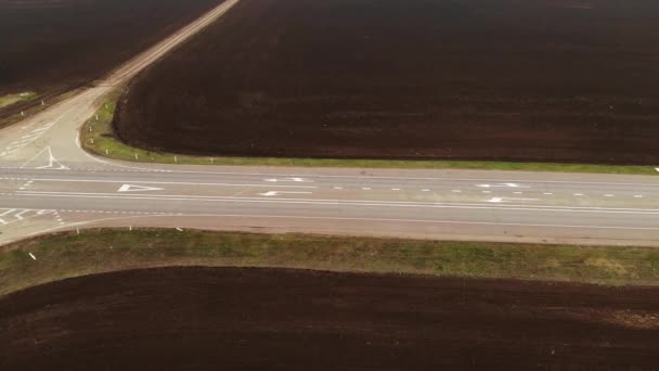 農村部のアスファルト高速道路の空中ビュー。車が高速道路に沿って移動している。車やトラックは田舎道を走る。高速道路の空気の映像道路周辺の田畑 — ストック動画