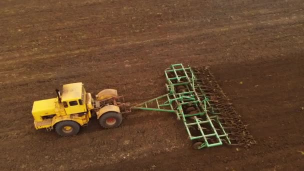 Vue aérienne d'un puissant tracteur jaune avec un grand effort sur le crochet effectuant le labour pour semer des cultures d'hiver avec un cultivateur à disque à l'automne 