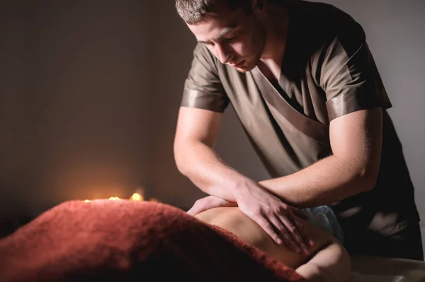 Primer plano de las manos de un masajista masculino haciendo masaje de espalda a una chica en el spa. Baja clave de alto contraste de poca profundidad de campo — Foto de Stock