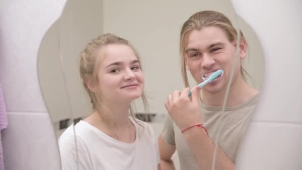 Jeune couple en brosse de bain dents ensemble, regardant dans le miroir. Gros plan — Video