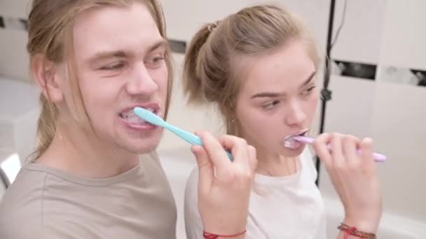 Young couple in bath brush teeth together, looking in mirror. Close-up — Stock Video