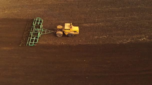 Vue aérienne d'un tracteur jaune avec une remorque labourant une terre labourant un champ cultivé avant de planter des céréales. Le concept de préparation de la terre pour planter des graines dans le sol. Exploitation agricole 