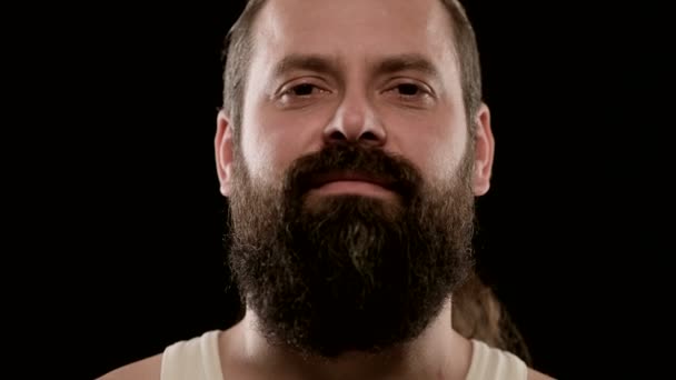 Homem bruto com barba, olha para a câmara arrogantemente. Grande close-up — Vídeo de Stock