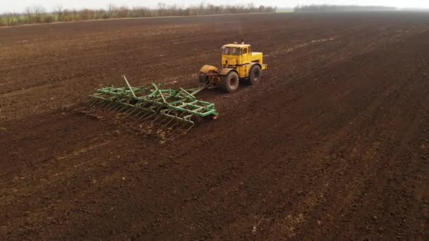 Vue aérienne d'un puissant tracteur jaune avec un grand effort sur le crochet effectuant le labour pour semer des cultures d'hiver avec un cultivateur à disque à l'automne 