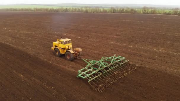 Vue aérienne d'un puissant tracteur jaune avec un grand effort sur le crochet effectuant le labour pour semer des cultures d'hiver avec un cultivateur à disque à l'automne 