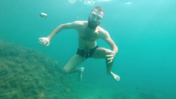 En tunn man med skägg i mask simmar under vattnet och viftar med armarna. Närbild. — Stockvideo