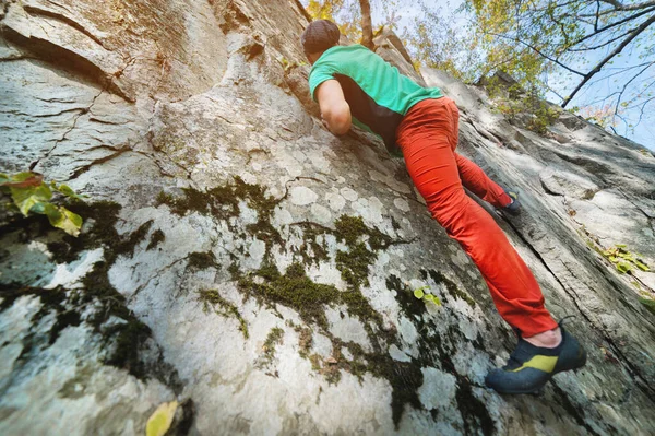 Ein frei gealterter männlicher Kletterer hängt an einer Felswand in einem Wald in den Bergen. Reifes Sportkonzept — Stockfoto