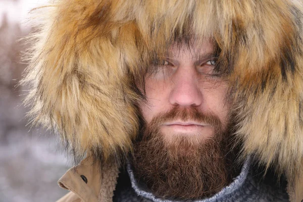 Um homem vestido com uma jaqueta casuais encapuzados outerwear popa de baixo do capô um retrato sério de uma pessoa na floresta de inverno. Tempo exterior — Fotografia de Stock