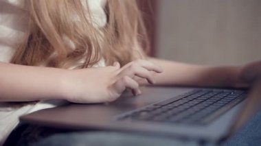 Laptop klavyesinde küçük bir kızın elinin sığ derinliği. Genç nesil aletleri kullanma fikri.