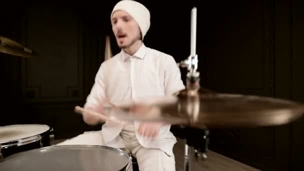 Fešák v bílém aktivně hraje na bicí soupravu na černém pozadí. Closeup — Stock video