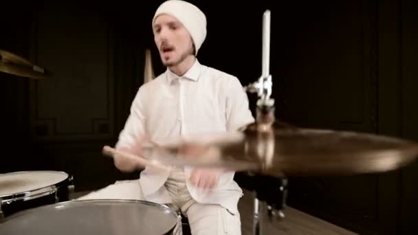 Handsome guy in white actively plays on drum kit in on black background. Closeup — Stock Video