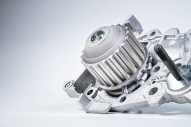 Gri arka planda bir su pompasının motorunu soğutmak için yeni metal otomobil pompası. Araba motoru için yeni yedek parça kavramı