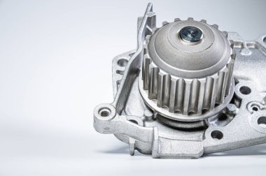 Gri arka planda bir su pompasının motorunu soğutmak için yeni metal otomobil pompası. Araba motoru için yeni yedek parça kavramı