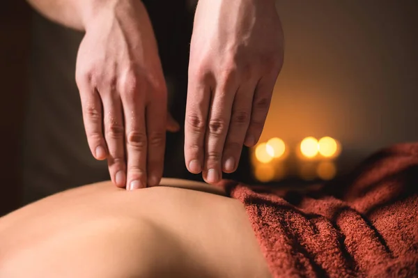 Close-up of the hands of a male masseur doing back finger massage to a girl at the spa. Low key high contrast shallow depth of field — Stock Photo, Image