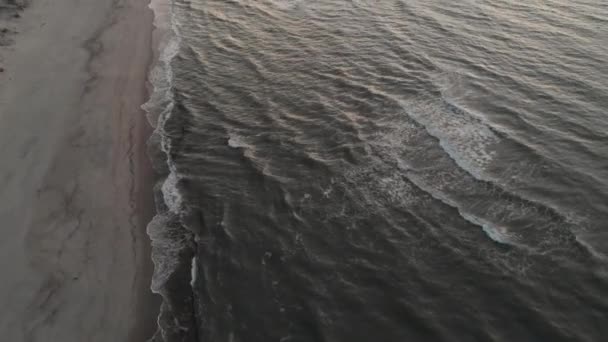 Luftaufnahme eines leisen Videos über einen tropischen Strand zu blauer Stunde nach Sonnenuntergang, das Abendaufnahmen von grün schäumenden Meereswellen zeigt, die auf die Küste krachen. Ansicht von oben ohne Menschen — Stockvideo