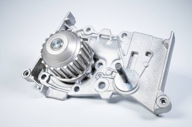 Gri arka planda bir su pompasının motorunu soğutmak için yeni metal otomobil pompası. Araba motoru için yeni yedek parça kavramı