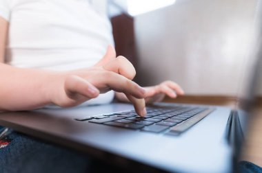 Laptop klavyesinde küçük bir kızın elinin sığ derinliği. Genç nesil aletleri kullanma fikri.