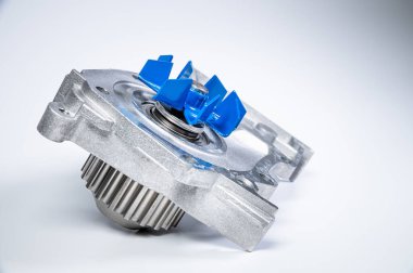 Gri arka planda bir su pompasının motorunu soğutmak için yeni metal otomobil pompası. Araba motoru için yeni yedek parça kavramı