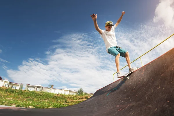 Porträt eines jungen Skateboarders, der an einem sonnigen Tag im Sommer auf einer Halfpipe-Rampe in einem Skatepark einen Trick auf seinem Skateboard macht. das Konzept der Jugendkultur von Freizeit und Sport — Stockfoto