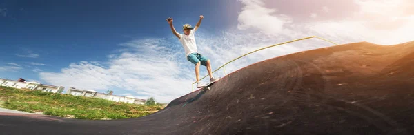 一个年轻的滑板选手在阳光灿烂的夏天在滑板公园的半管斜坡上玩滑板把戏的肖像。 青年休闲和体育文化的概念 — 图库照片