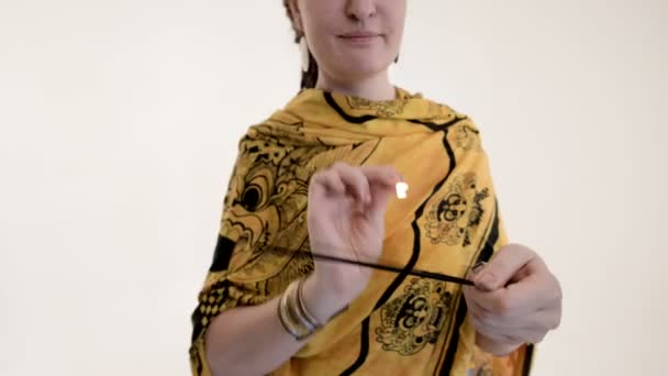 Mujer con rastas enciende varillas de incienso con fósforo en estudio blanco. Primer plano. — Vídeos de Stock