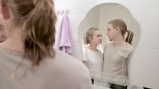 Νεαρό ζευγάρι στέκεται στο λευκό μπάνιο και κοιτάζοντας αντανάκλαση στον καθρέφτη — Αρχείο Βίντεο