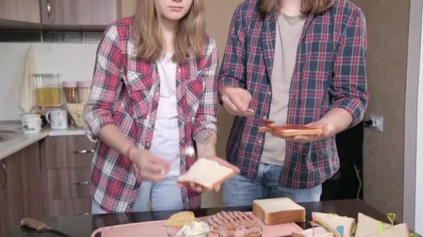 Joven hombre y mujer están cocinando sándwiches juntos. Primer plano — Vídeo de stock