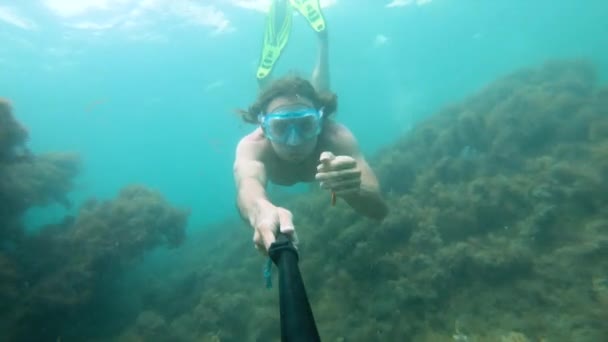 Hombre musculoso con máscara nada bajo el agua, sosteniendo la cámara delante. Primer plano . — Vídeos de Stock