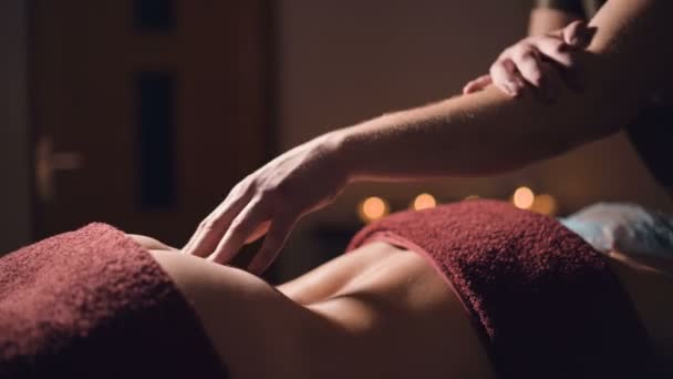 Main masculine d'un masseur physiothérapeute professionnel faisant un massage lombaire à une patiente dans une chambre de luxe de massage avec une lumière tamisée — Video