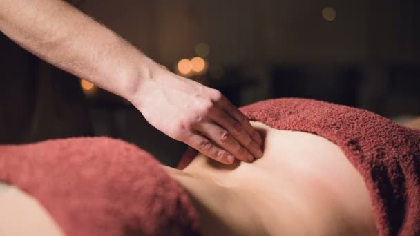 Close-up hands Masaje profesional premium en un gabinete atmosférico oscuro. Joven hombre haciendo masaje a una cliente femenina en una oficina oscura en el fondo de velas encendidas — Vídeo de stock
