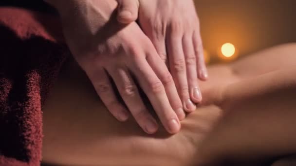Close-up van premium anti-cellulitis dijmassage. Mannelijke handen doen wellness massage van de dij aan het geduldige meisje in een gezellige studie met schemerig licht. Luxe massagediensten — Stockvideo