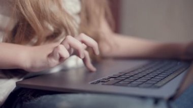 Laptop klavyesinde küçük bir kızın elinin sığ derinliği. Genç nesil aletleri kullanma fikri.