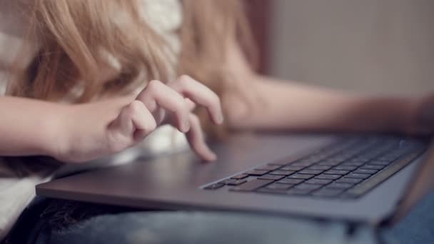 Closeup profundidade rasa de campo de uma pequena mão de meninas em um teclado de computador portátil. O conceito de usar a geração mais jovem de gadgets — Vídeo de Stock