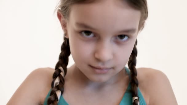 Girl with pigtails, brown eyes angrily tearing toy bear on white background. — Stock Video