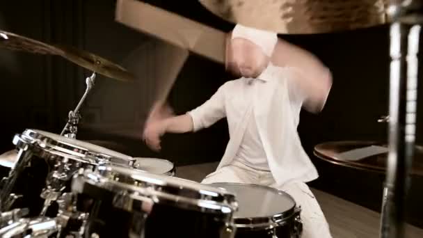 Fešák v bílém aktivně hraje na bicí soupravu na černém pozadí. Closeup — Stock video