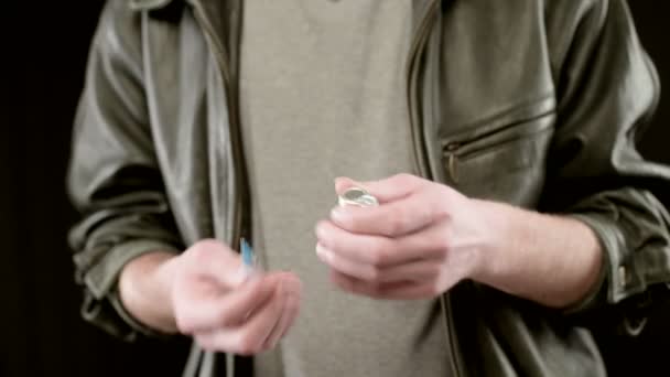 Man in leather jacket is holding an ampoule in hands fills syringe. Close-up — Stock Video