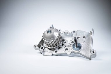 Gri arka planda bir su pompasının motorunu soğutmak için yeni metal otomobil pompası. Araba motoru için yeni yedek parça kavramı
