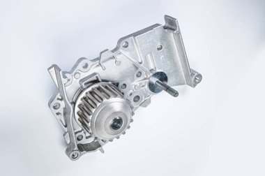 Gri arka planda bir su pompasının motorunu soğutmak için yeni metal otomobil pompası. Araba motoru için yeni yedek parça kavramı