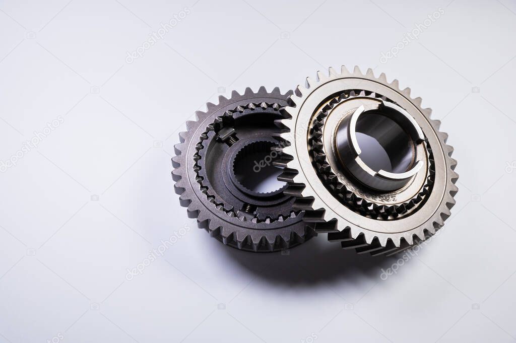 New parts on a gray background. Gears of gear shifting torque transmission. Conceptually mechanical background. Shiny gear box gear teeth