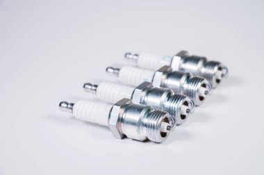 Şüpheli gri arka planda ateş ediyor. Yeni dört buji, benzin motoru için yedek parça. Yeni otomobil parçaları ve bakım kavramı