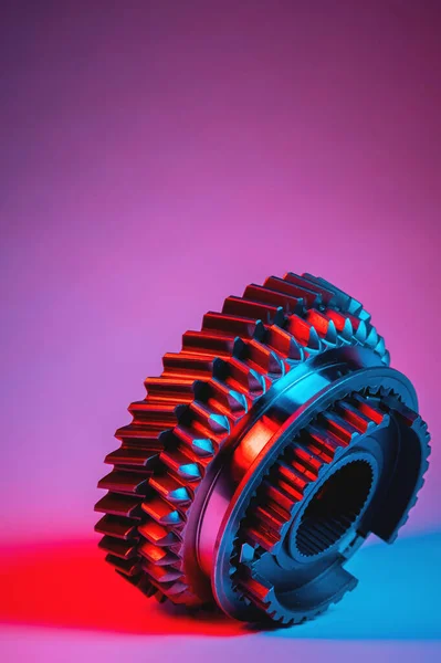 New parts in the conceptual design of a neon hi-tech style. Gears of gear shifting torque transmission. Conceptually mechanical background. Shiny gear teeth of a gearbox in blue-red lighting. — Stock Photo, Image