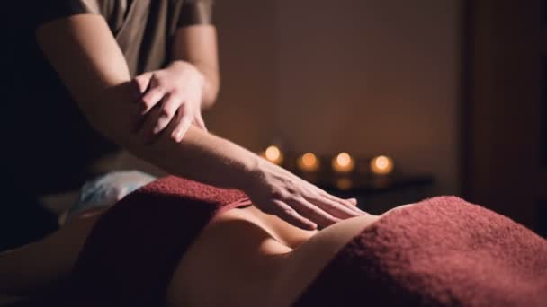 Närbild händer Professionell premium massage i en mörk atmosfärisk skåp. Ung man gör massage till en kvinnlig klient i ett mörkt kontor på bakgrunden av brinnande ljus — Stockvideo