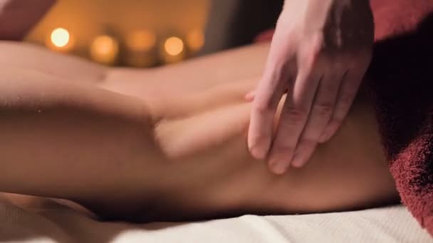 Close-up of premium anti-cellulite thigh massage. Male hands do wellness massage of the thigh to the patient girl in a cozy study with dim light. Luxury massage services — Stock Video