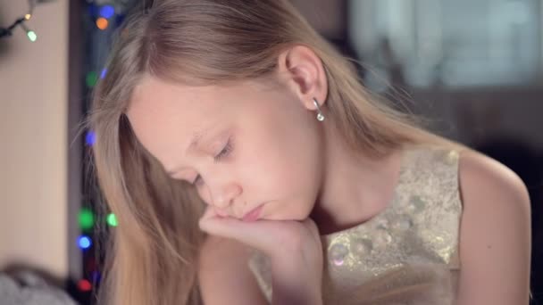 Egy kis szomorú csalódott lány ül egy mesterséges kandalló és szomorú mellett puha játékok. Az elkényeztetett karácsonyi ünnep fogalma — Stock videók