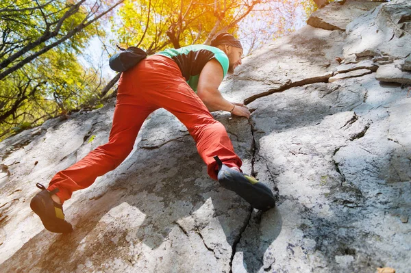 Un escalador macho de edad libre cuelga en una pared de roca en un bosque en las montañas. Concepto deportivo maduro — Foto de Stock